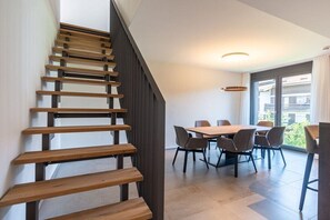 A staircase with wooden steps leading to a dining area with a table and chairs. - Villa Alpjuwel-Himmelblick (Oberstdorf)
