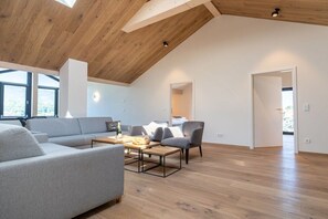 A spacious living area with a high ceiling, a sofa, armchairs, and a coffee table. - Villa Alpjuwel-Himmelblick (Oberstdorf)