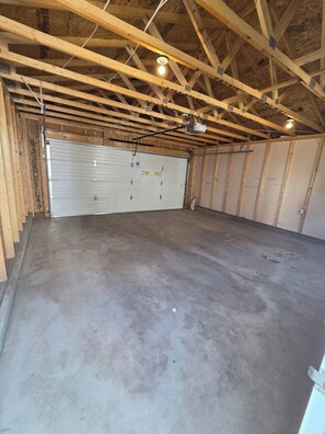 A large, unfinished garage with a concrete floor and wooden beams. - Spacious Family House in Edmonton - Perfect for a Comfortable Stay (Edmonton)