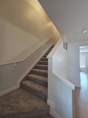 A carpeted staircase with white handrails and walls, leading to a landing with a door. - Spacious Family House in Edmonton - Perfect for a Comfortable Stay (Edmonton)