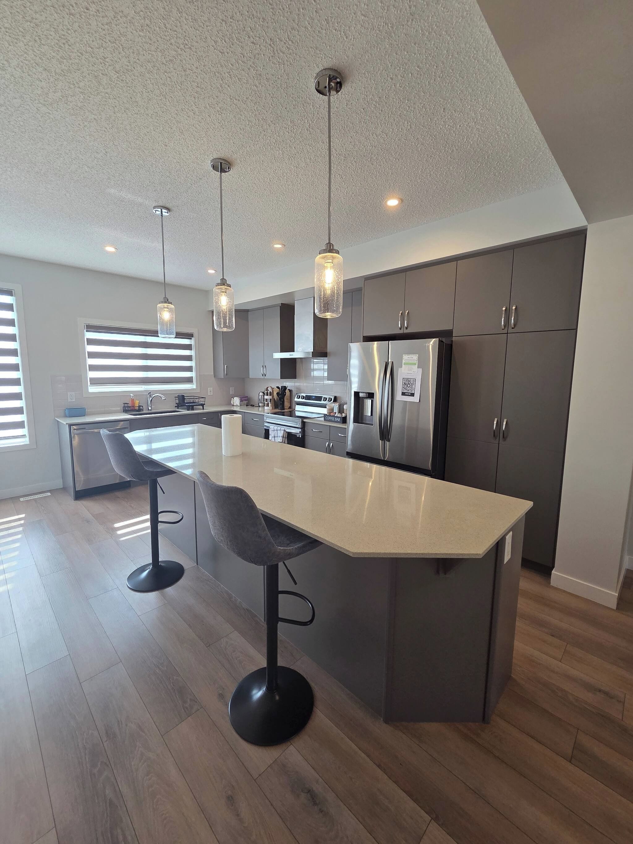 A modern kitchen with a central island, stainless steel appliances, and pendant lighting.