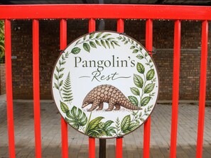 A circular sign with a pangolin illustration and the text 'Pangolin's Rest' against a brick wall background.