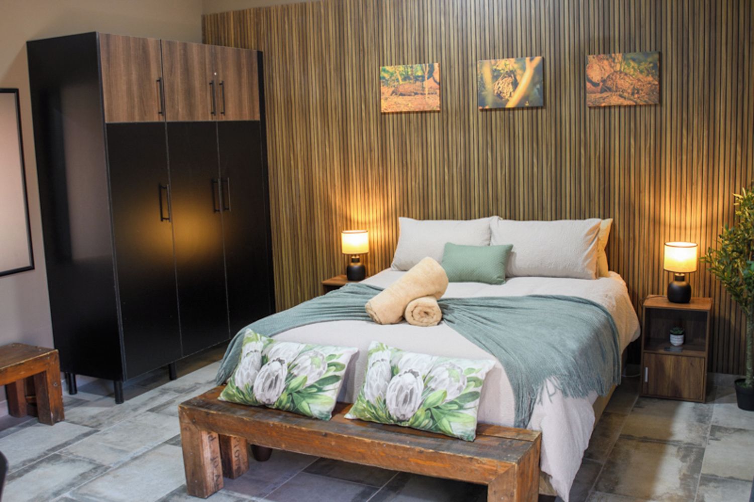 Een slaapkamer met een bed, nachtkastjes, een kledingkast en wanddecoratie.