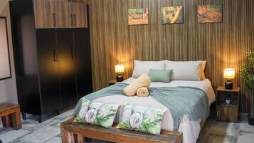 Een slaapkamer met een bed, nachtkastjes, een kledingkast en wanddecoratie.
