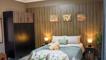A bedroom with a bed, a wardrobe, and a wall with vertical wooden slats.