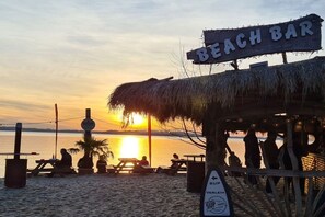 Eine Strandbar mit einem Reetdach und einem Schild, das eine Strandbar anzeigt.