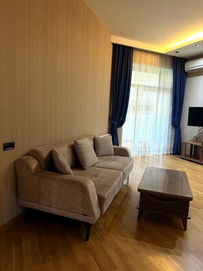 A living room with a sofa, a coffee table, and a television. - Baku Bulvar 3BR Luxury Apartment (Baku)