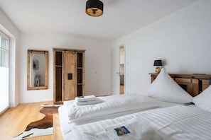 Ein Schlafzimmer mit zwei Betten, einem Holzschrank, einem Spiegel und einer Lampe.