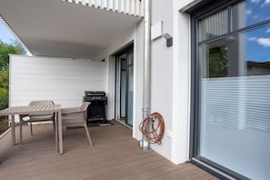 A covered outdoor area with a grill, a table, and chairs. - Breitbrunn am Chiemsee (Breitbrunn am Chiemsee)