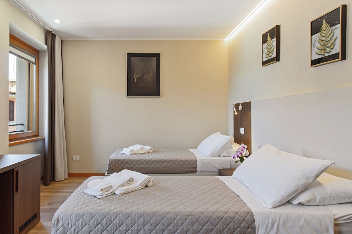 A hotel room with a bed, a desk, a TV, and a window.