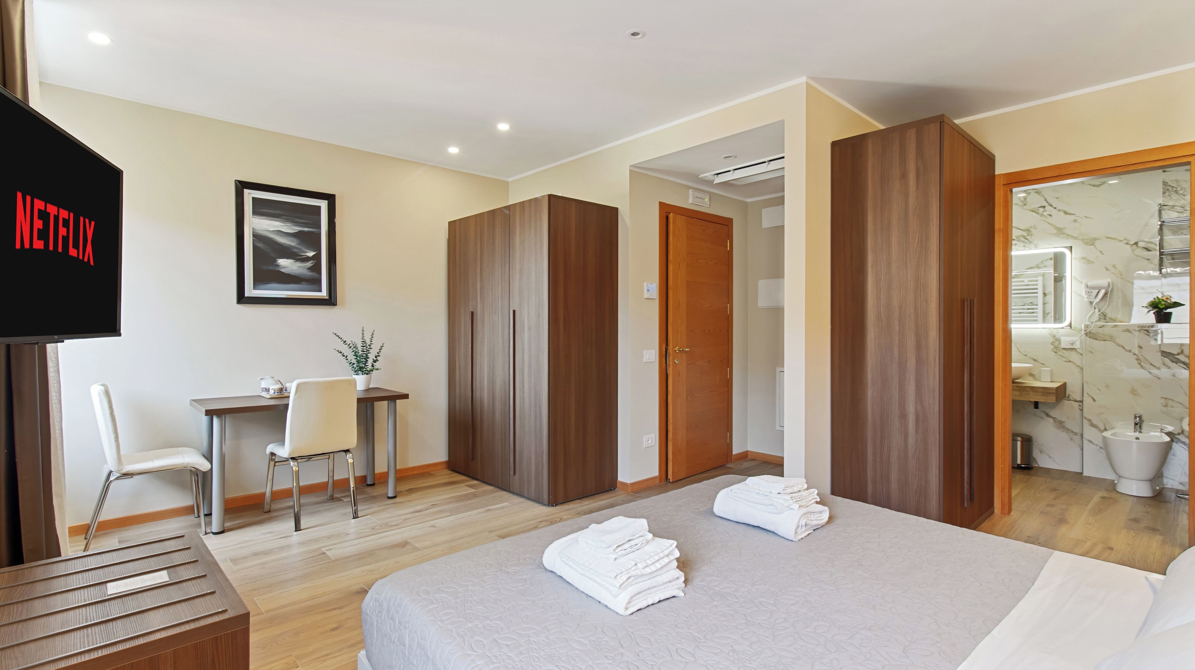 Una habitación de hotel con cama, escritorio, silla, televisor y baño.
