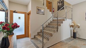 Una escalera con barandilla de metal, una puerta de madera y un jarrón con flores.