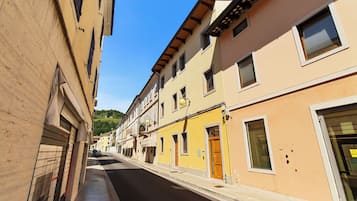 Una calle estrecha flanqueada por edificios de varios pisos, algunos con balcones y ventanas, bajo un cielo despejado.