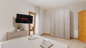 A hotel room with a bed, a TV mounted on the wall, a wardrobe, and a door.