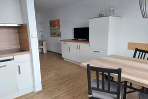 A compact kitchen with white cabinets, a wooden countertop, and a television on top. - Small holiday home Allgäublick (Bad HIndelang)