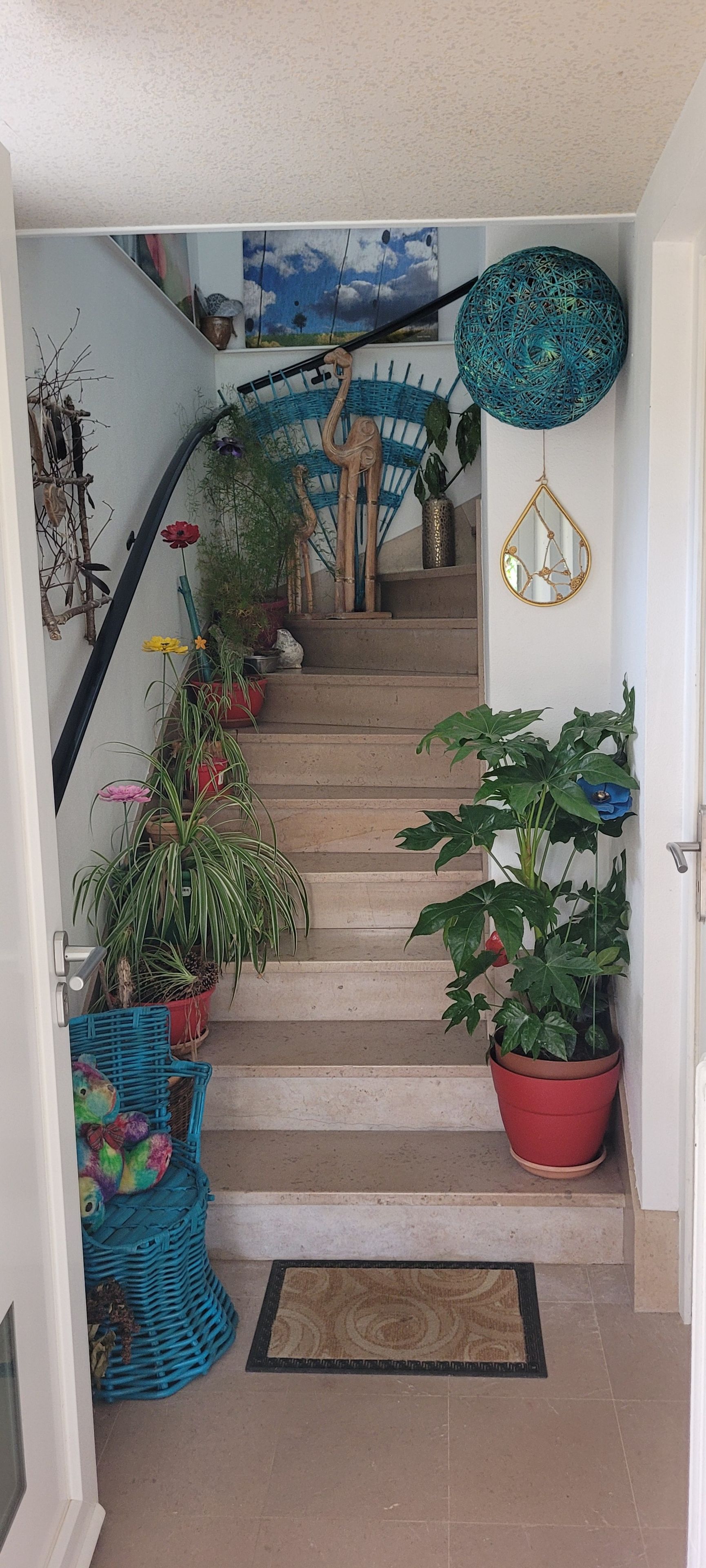 A staircase with potted plants, a woven basket, and a mirror.