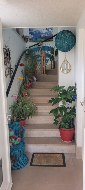 Una escalera con plantas en macetas, una cesta tejida y un espejo.