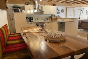 A kitchen with a wooden table, a microwave, and cabinets. - Organic farm with 3 bedrooms (Elzach, Heidburg)