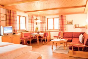 A cozy room with a bed, a dining area with a table and chairs, a sofa, and a television. - Holiday apartment with 1 bedroom (Balderschwang)