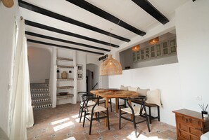 A dining area with a round wooden table, black chairs, and a woven pendant light. - Cave Home | Sea and Mountain Views in Mijas Pueblo (Mijas Pueblo)