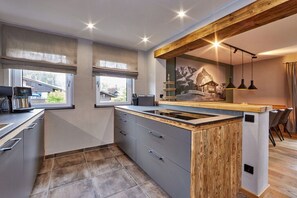 A modern kitchen with a central island, large windows, and a rustic wooden ceiling. - Holiday apartment with 1 bedroom (Garmisch-Partenkirchen)