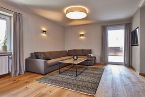 Uma sala de estar moderna com um sofá seccional, uma mesa de centro e um tapete estampado.