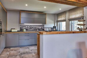 Eine moderne Küche mit grauen Schränken, einer Holzarbeitsplatte und einer Spritzschutzleiste im Bergdesign.