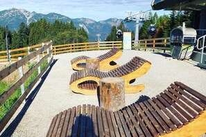Eine Holzterrasse mit Bänken, einem Holzmast und Blick auf die Berge.