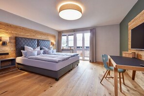 A modern bedroom with a bed, bedside table, and a dining area with a table and chairs. - Holiday apartment with 1 bedroom (Garmisch-Partenkirchen)