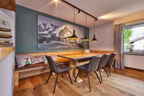 Ein Essbereich mit einem Holztisch, schwarzen Stühlen, einer Bank mit Kissen und einem großen Schwarz-Weiß-Foto an der Wand.