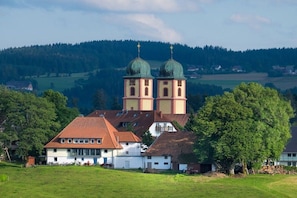 A church with two domes and a bell tower, surrounded by residential buildings and greenery. - Holiday apartment with 3 bedrooms (St. Märgen)