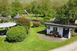 A small, single-story building with a patio area, surrounded by well-maintained gardens and trees. - Holiday apartment with 2 bedrooms (Bernkastel-kues OT Andel)