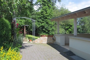 A garden with a pergola, stone steps, and a pathway leading to a covered area. - Holiday home in Pluwig with swimming pool (Pluwig)