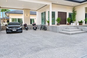 A modern building with a car and two motorcycles parked in front. - Private 5-Bedroom Pool Villa in Middle of the Island Phuket (Tambon Kathu)