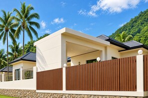 Uma casa moderna com telhado plano, base de pedra e cerca de madeira.