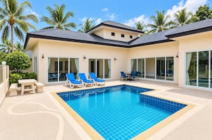 A modern poolside area with a rectangular pool, lounge chairs, and a dining table. - Private 5-Bedroom Pool Villa in Middle of the Island Phuket (Tambon Kathu)