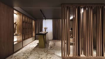Un interior moderno con piso de mármol, paneles de madera y una mesa central con un florero.