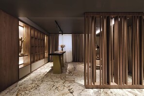 Un interior moderno con piso de mármol, paneles de madera y una mesa central con un florero.