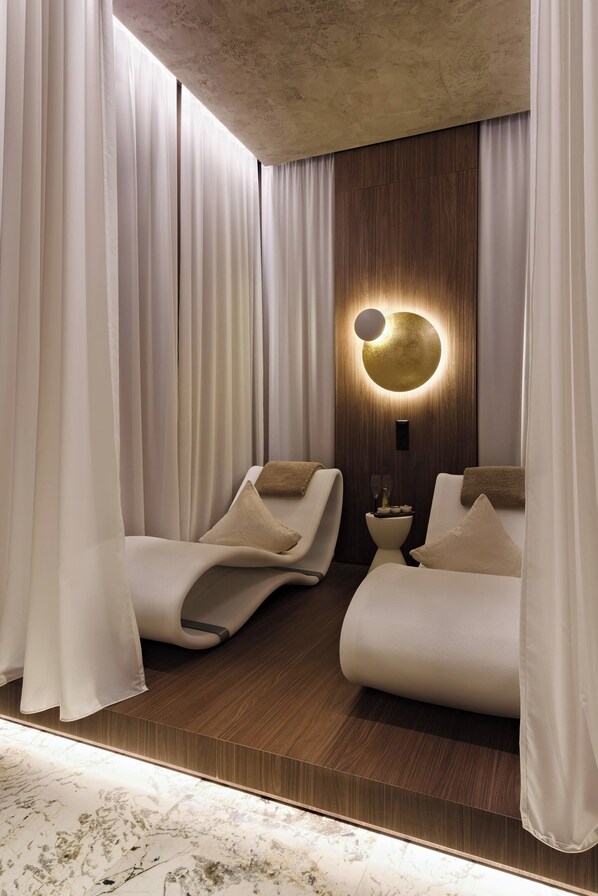 Un dormitorio moderno con dos camas, un panel de pared de madera y una lámpara circular.
