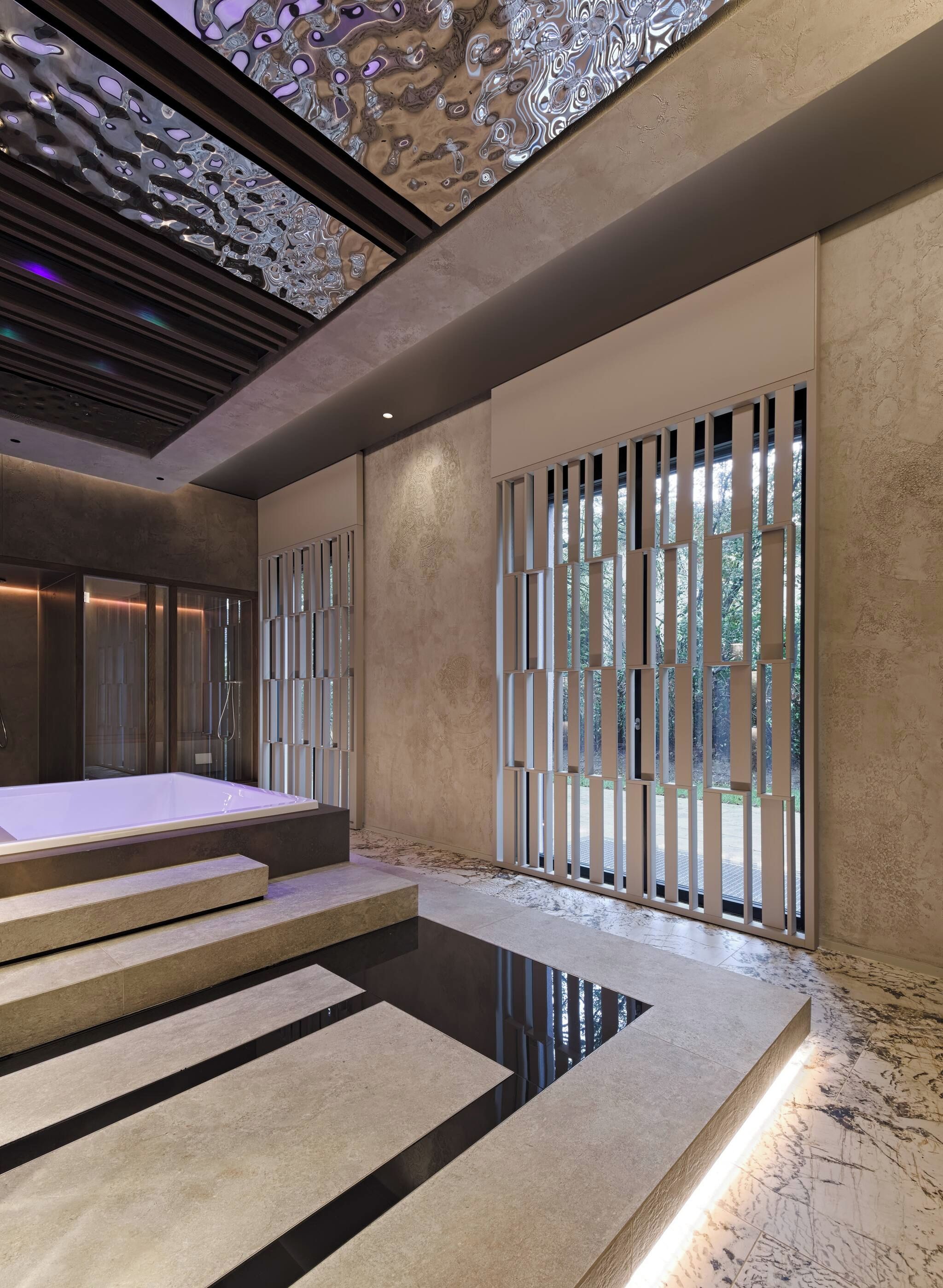 Un spa moderno con una bañera grande, suelo de piedra y un plafón con una lámpara original.