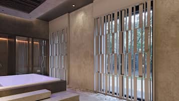 Un spa moderno con una bañera grande, suelo de piedra y un plafón con una lámpara original.