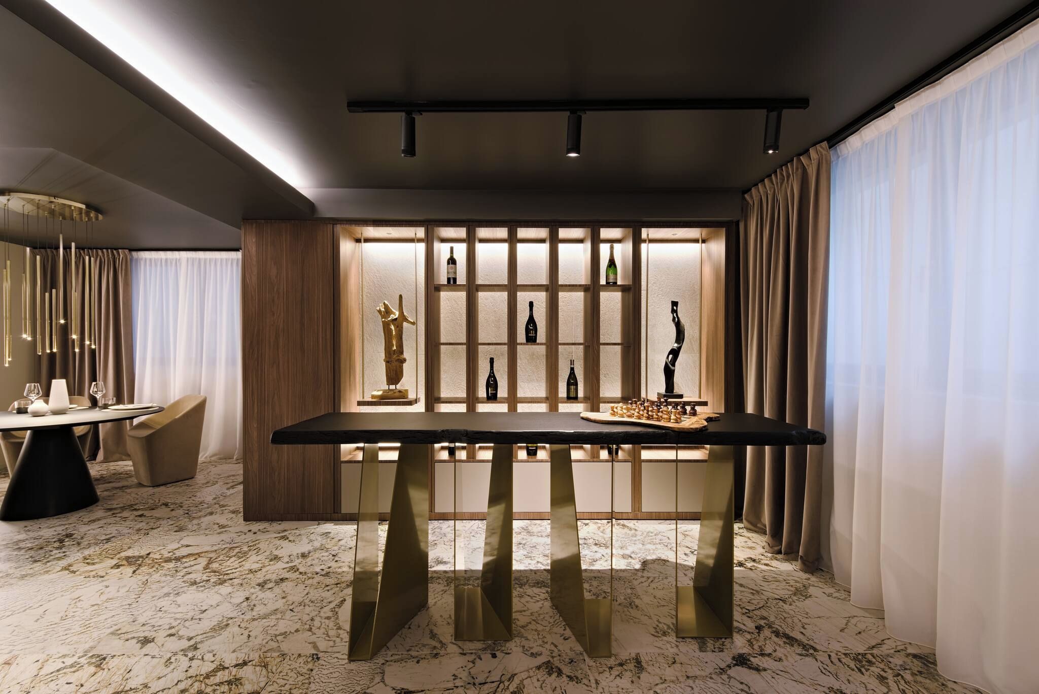 Un comedor moderno con piso de mármol, una mesa central y una vitrina para exhibir vinos.