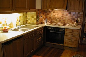A kitchen with wooden cabinets, a dishwasher, an oven, and a tiled backsplash. - Holiday apartment with 1 bedroom (Oy-Mittelberg)