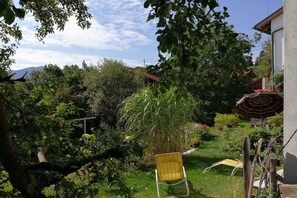 A garden with a yellow chair, a wooden fence, and a building in the background. - Holiday apartment with 1 bedroom (Oy-Mittelberg)