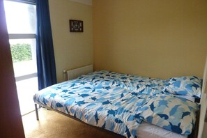 A bedroom with a bed, a radiator, a window with curtains, and a picture on the wall. - Water Villa Lisdodde (Workum)