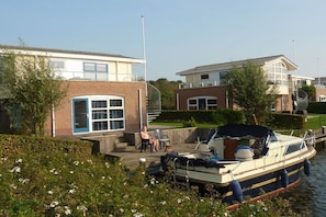 A residential area with houses, a dock, and a boat. - Water Villa Lisdodde (Workum)