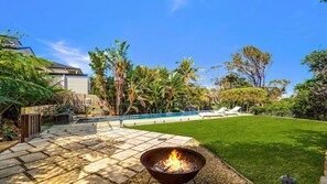 A backyard with a swimming pool, a fire pit, and a well-maintained lawn. - The Sanctuary Killcare by HolidayCo. (KILLCARE HEIGHTS)