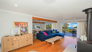 Ein Wohnzimmer mit blauem Sofa, Holzschrank und Essbereich mit Tisch und Stühlen.