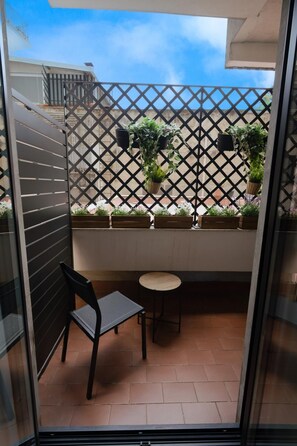 A balcony with a chair, a small table, and potted plants. - Charming Catania Apartment with Balcony (Città metropolitana di Catania)