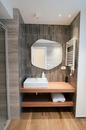 A modern bathroom with a rectangular sink, a mirror, and a towel on a shelf. - Charming Catania Apartment with Balcony (Città metropolitana di Catania)